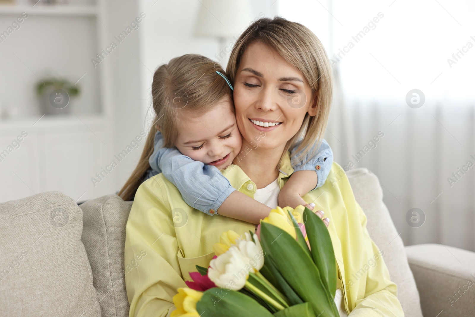 Photo of Little daughter congratulating her mom with bouquet of beautiful tulips at home. Happy Mother's Day