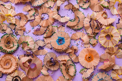Photo of Wooden pencil shavings and colorful crumbs on violet background, flat lay
