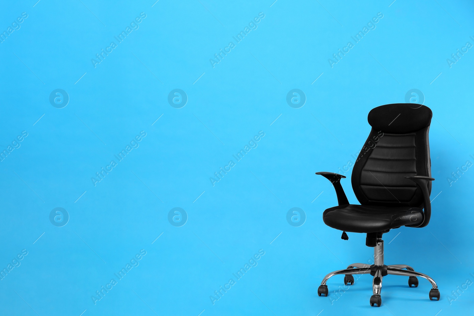 Photo of Comfortable office chair on light blue background, space for text