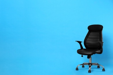 Comfortable office chair on light blue background, space for text