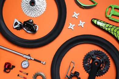 Set of different bicycle tools and parts on orange background, flat lay