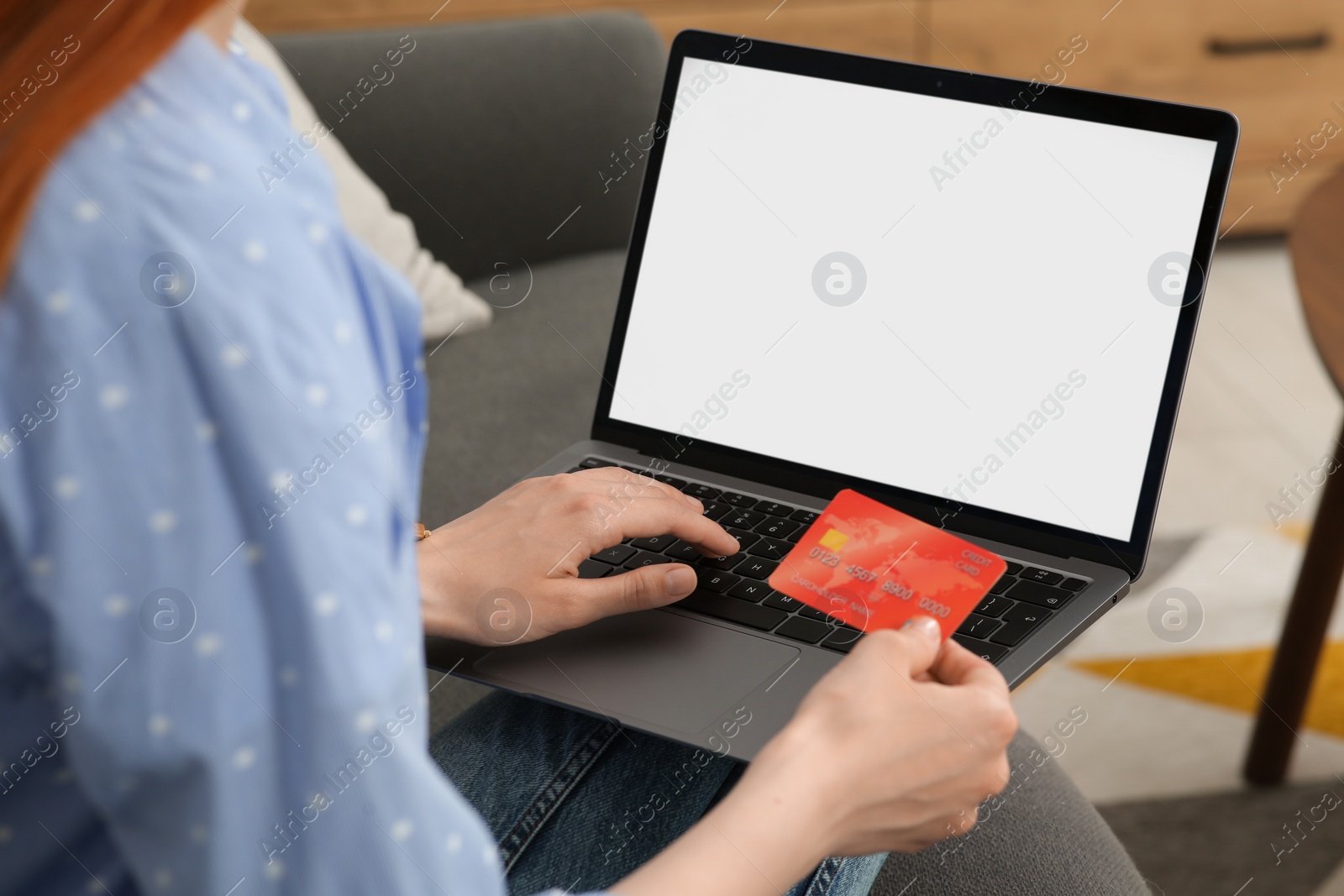 Photo of Woman with credit card using laptop for online shopping on sofa indoors, closeup