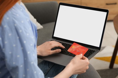 Photo of Woman with credit card using laptop for online shopping on sofa indoors, closeup