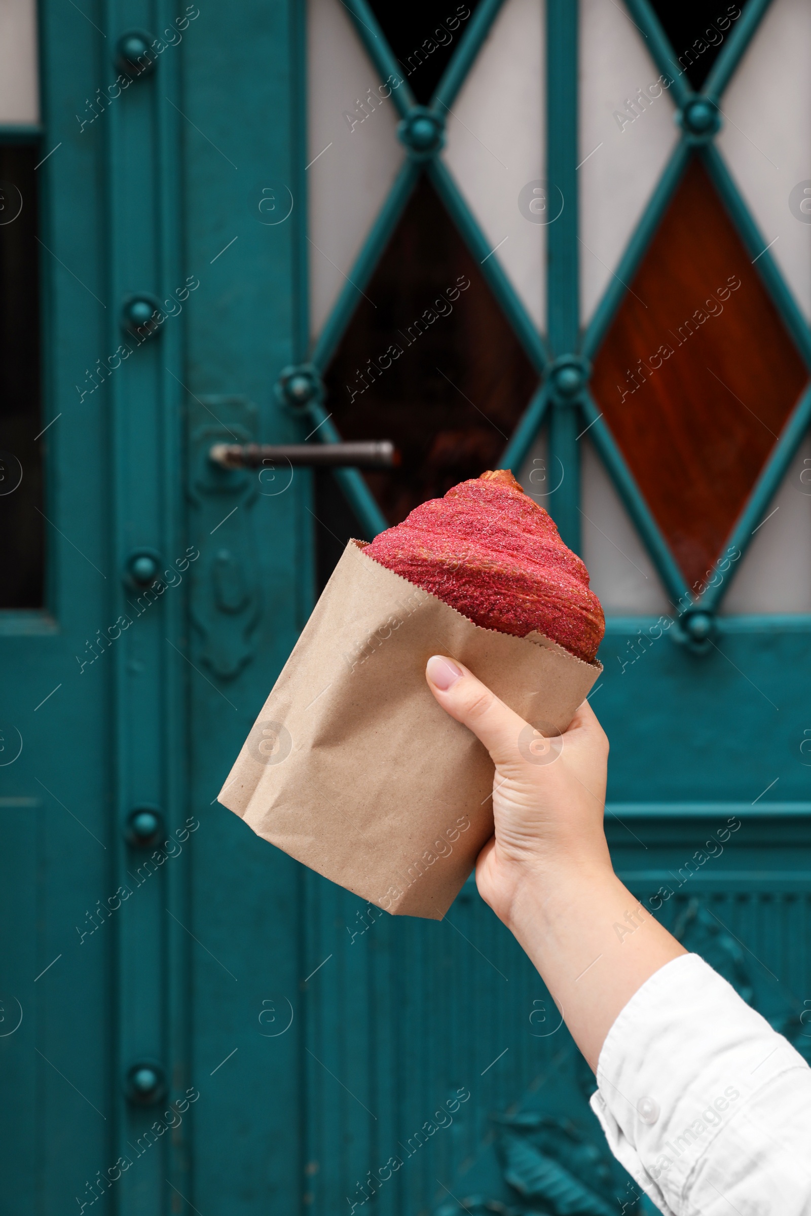 Photo of Woman holding croissant near blue door, closeup