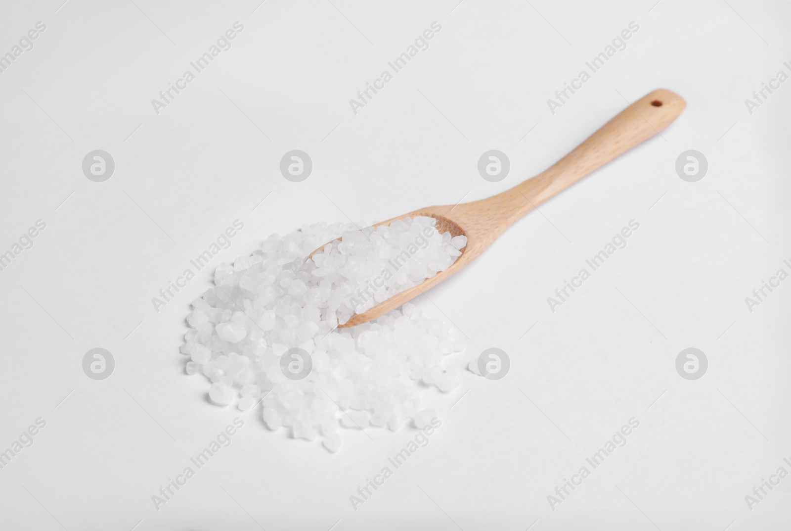 Photo of Wooden spoon with natural sea salt isolated on white