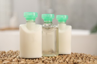 Photo of Mini bottles of cosmetic products on wicker mat against blurred background, closeup