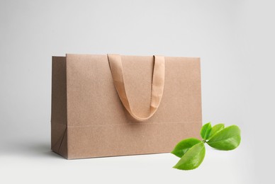 Image of Paper shopping bag and green leaves on white background. Eco friendly lifestyle