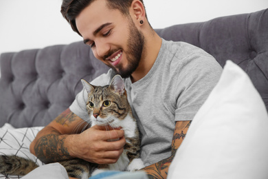 Photo of Happy man with cat on bed at home. Friendly pet