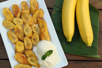 Tasty deep fried banana slices with ice cream and fresh fruits on wooden table, flat lay