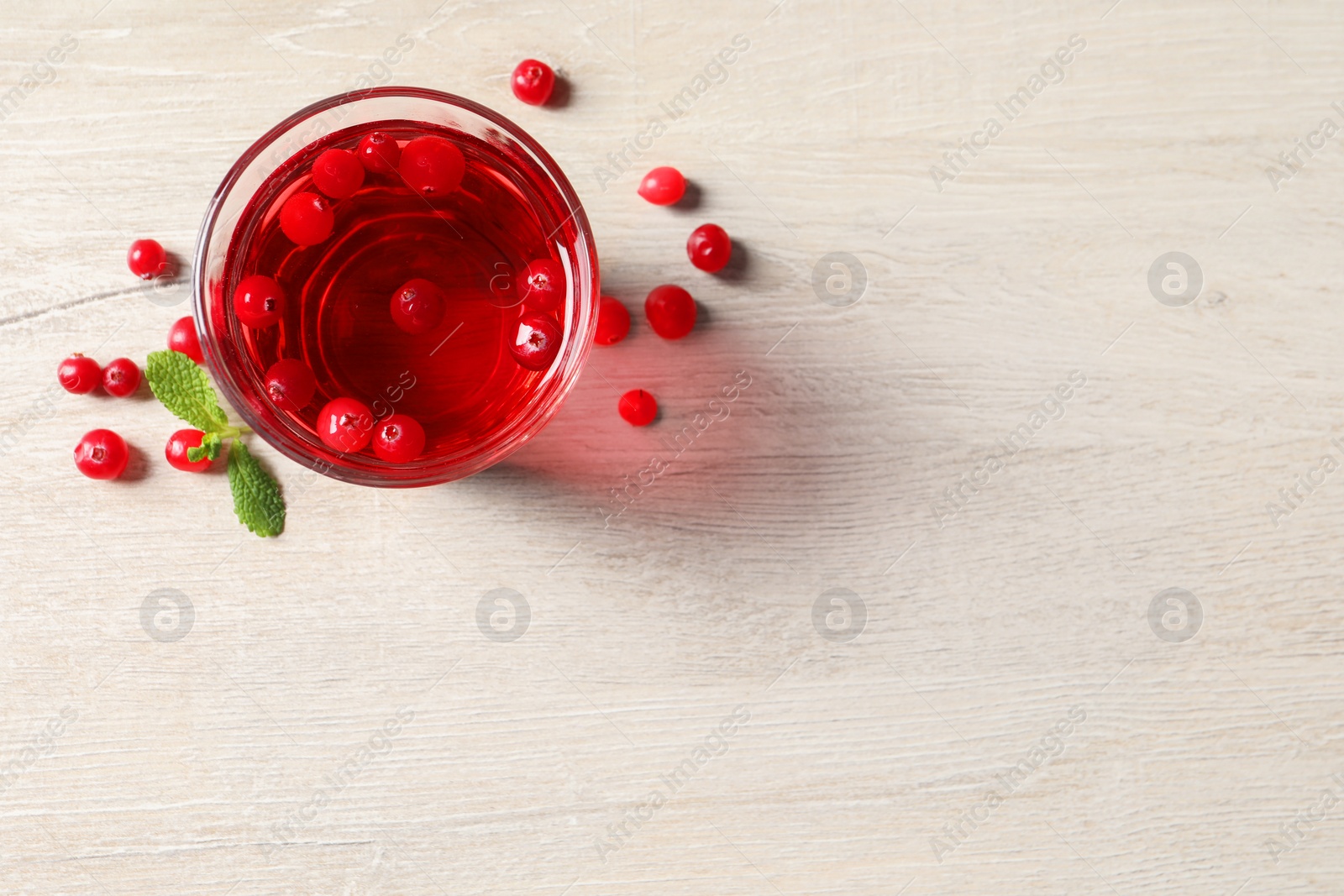 Photo of Tasty refreshing cranberry juice, mint and fresh berries on light wooden table, flat lay. Space for text