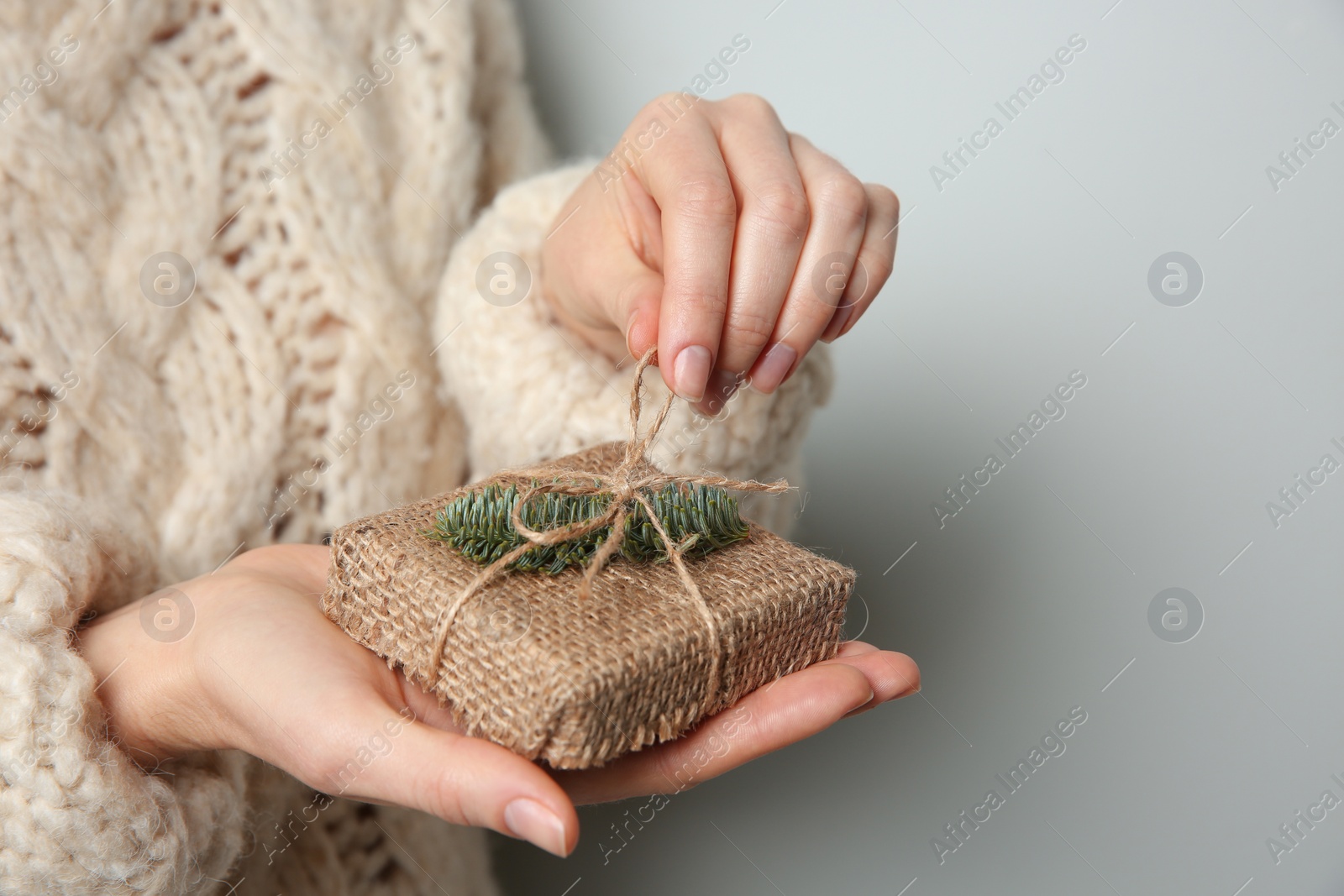 Photo of Woman holding Christmas gift box on grey background, closeup