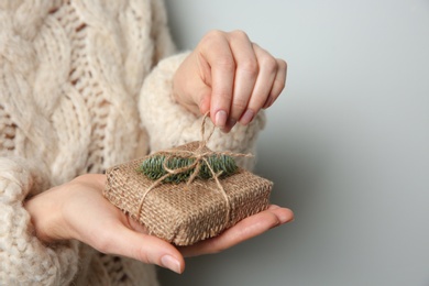 Photo of Woman holding Christmas gift box on grey background, closeup