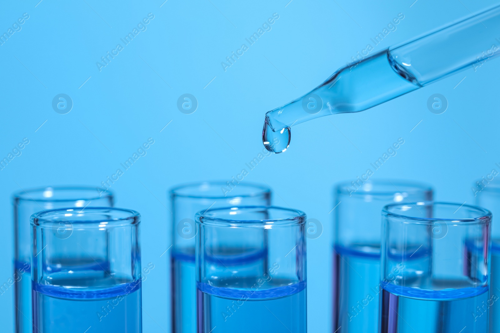 Photo of Dripping reagent into test tube on light blue background, closeup and space for text. Laboratory analysis