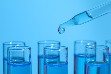 Photo of Dripping reagent into test tube on light blue background, closeup and space for text. Laboratory analysis