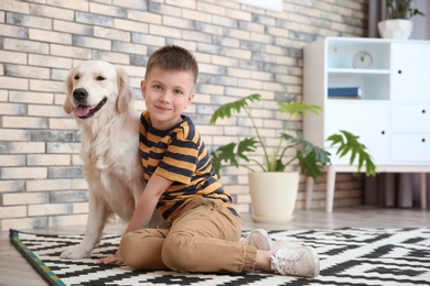 Cute little child with his pet on floor at home