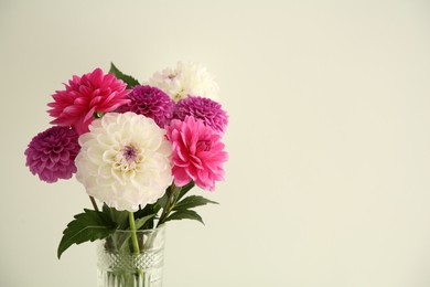 Photo of Bouquet of beautiful Dahlia flowers near white wall, space for text