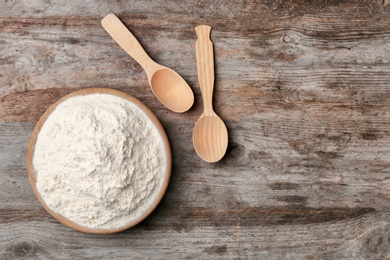 Photo of Bowl with flour on wooden background