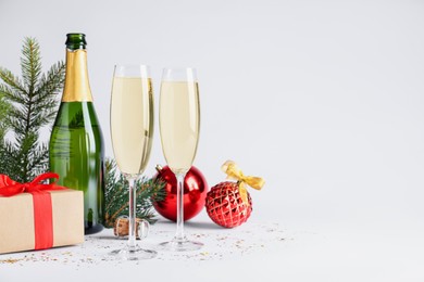 Photo of Happy New Year! Bottle of sparkling wine, glasses and festive decor on white background, space for text