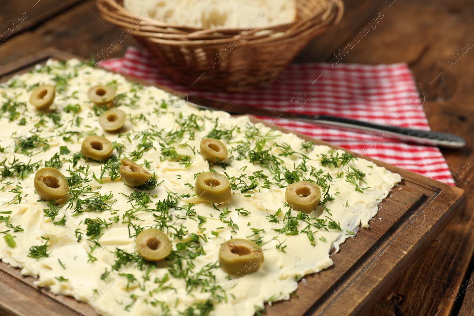 Photo of Fresh butter board with cut olives and dill on wooden table, closeup