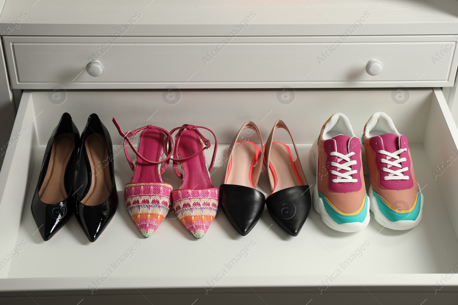 Photo of Different women's shoes in open drawer. Footwear storage