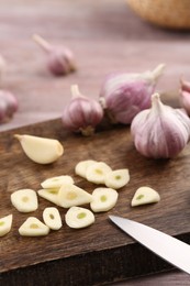 Photo of Fresh garlic and knife on table, closeup