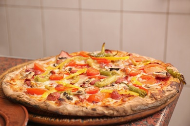 Photo of Wooden board with delicious pizza on table in restaurant. Fresh from oven