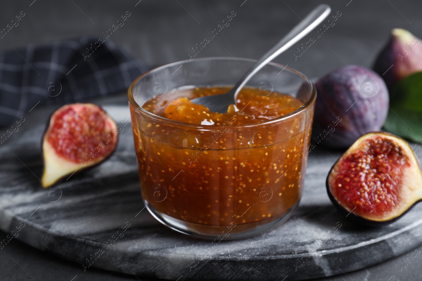 Photo of Delicious fig jam and fresh fruit on grey table, closeup