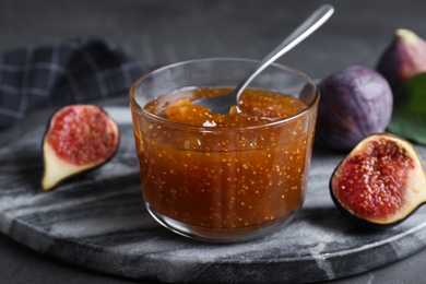 Delicious fig jam and fresh fruit on grey table, closeup