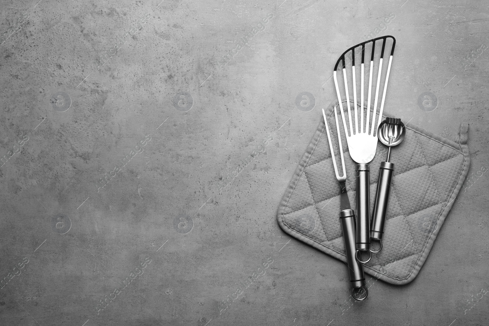 Photo of Different kitchen utensils and potholder on grey background, top view with space for text