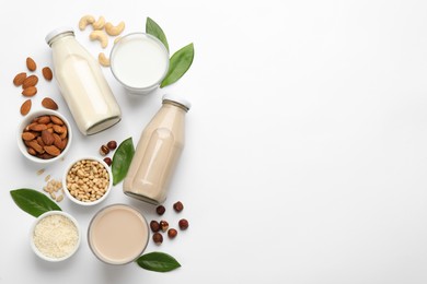Photo of Different vegan milks and ingredients on white background, flat lay. Space for text