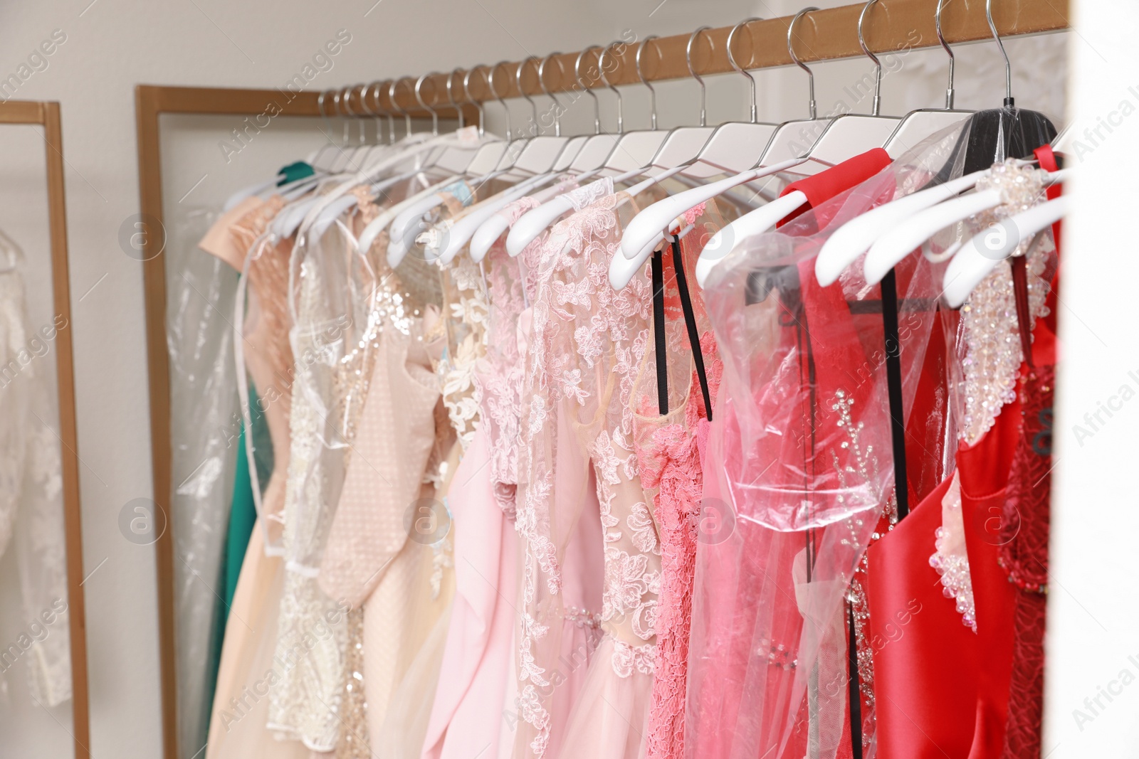 Photo of Different beautiful dresses on hangers in rental clothing salon