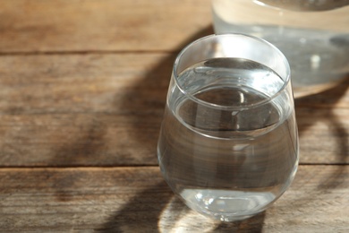Glass of water on wooden table, closeup with space for text. Refreshing drink