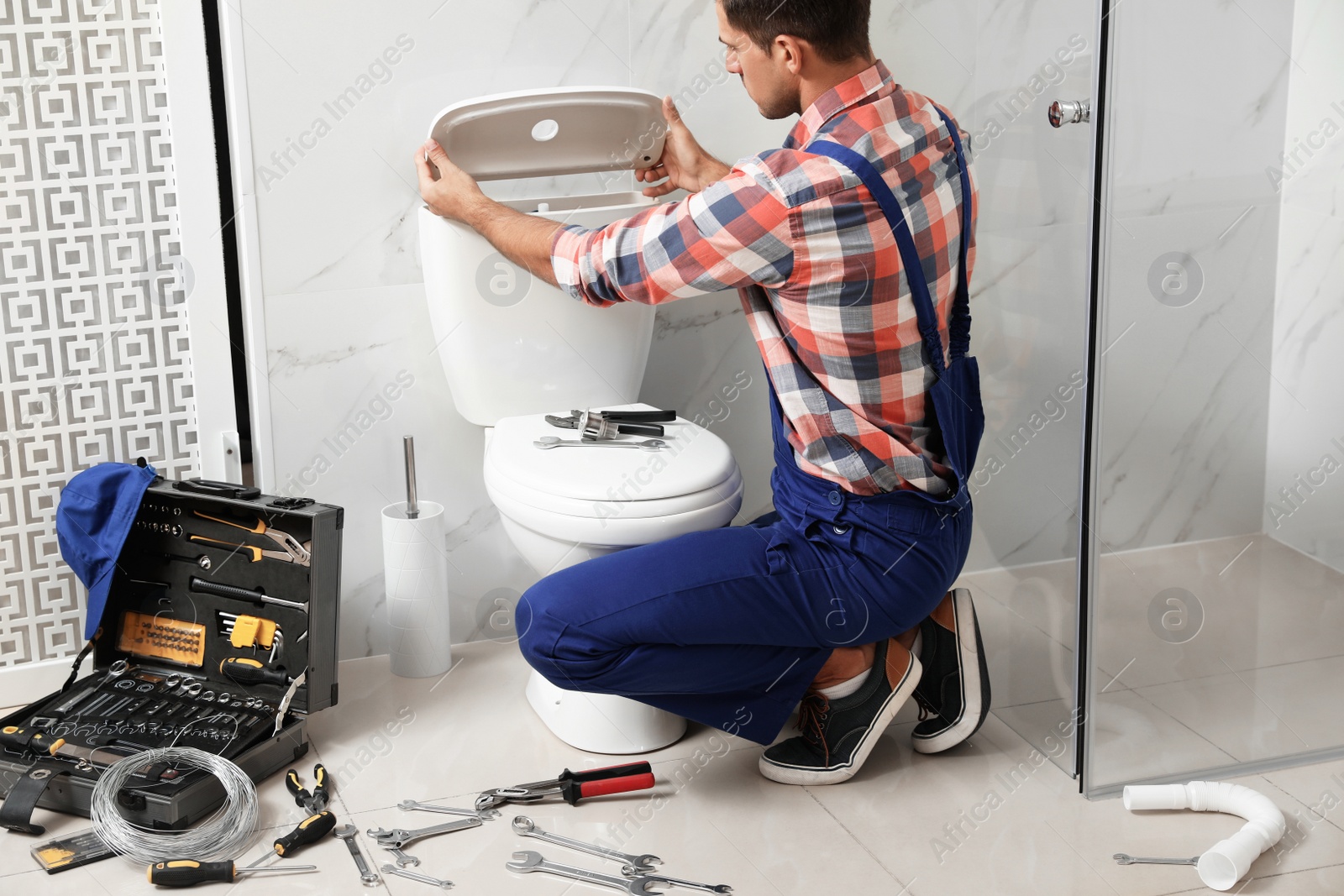 Photo of Professional plumber working with toilet bowl in bathroom