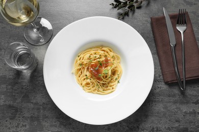 Photo of Tasty spaghetti with prosciutto and microgreens served on grey table, flat lay. Exquisite presentation of pasta dish