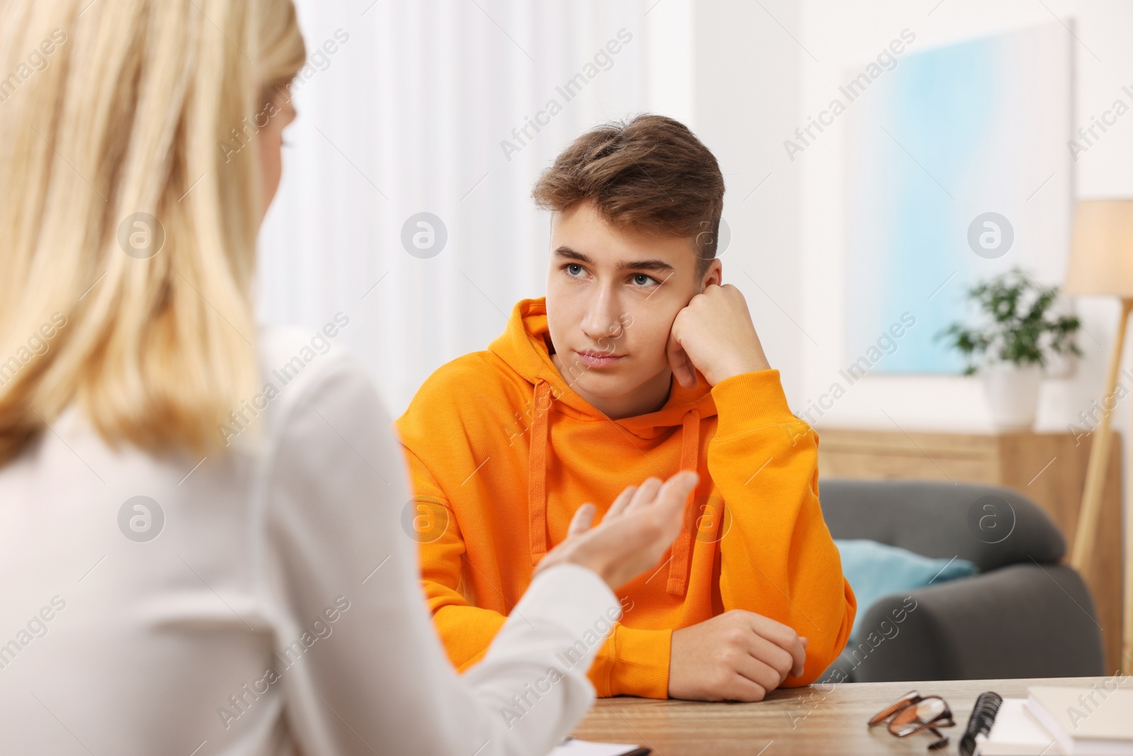 Photo of Psychologist working with teenage boy at table in office