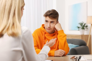 Photo of Psychologist working with teenage boy at table in office