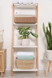 Soft towels on decorative ladder near white wall