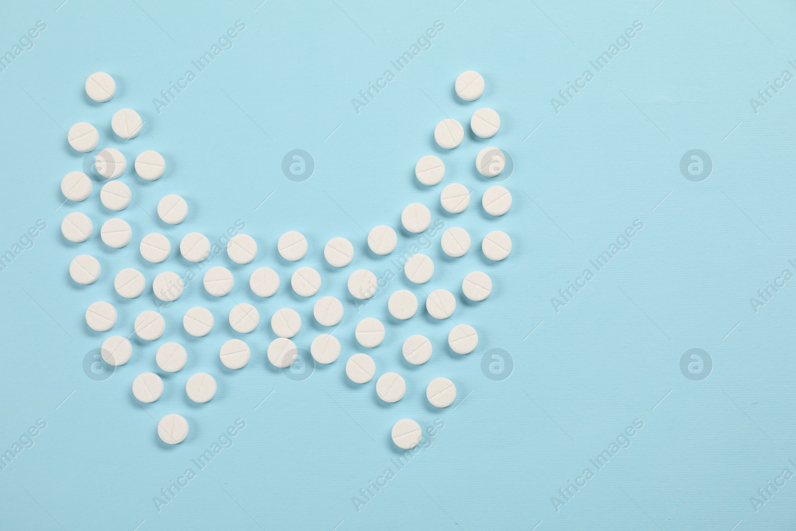 Photo of Endocrinology, Shape of thyroid gland made of pills on light blue background, flat lay. Space for text