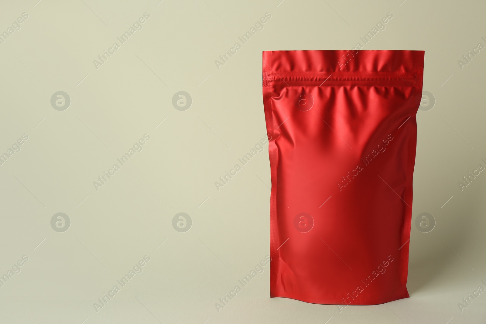 Photo of One blank foil package on beige background. Space for text