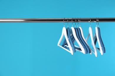 Photo of Metal rack with clothes hangers on color background, space for text