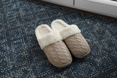 Photo of Pair of beautiful soft slippers on mat indoors