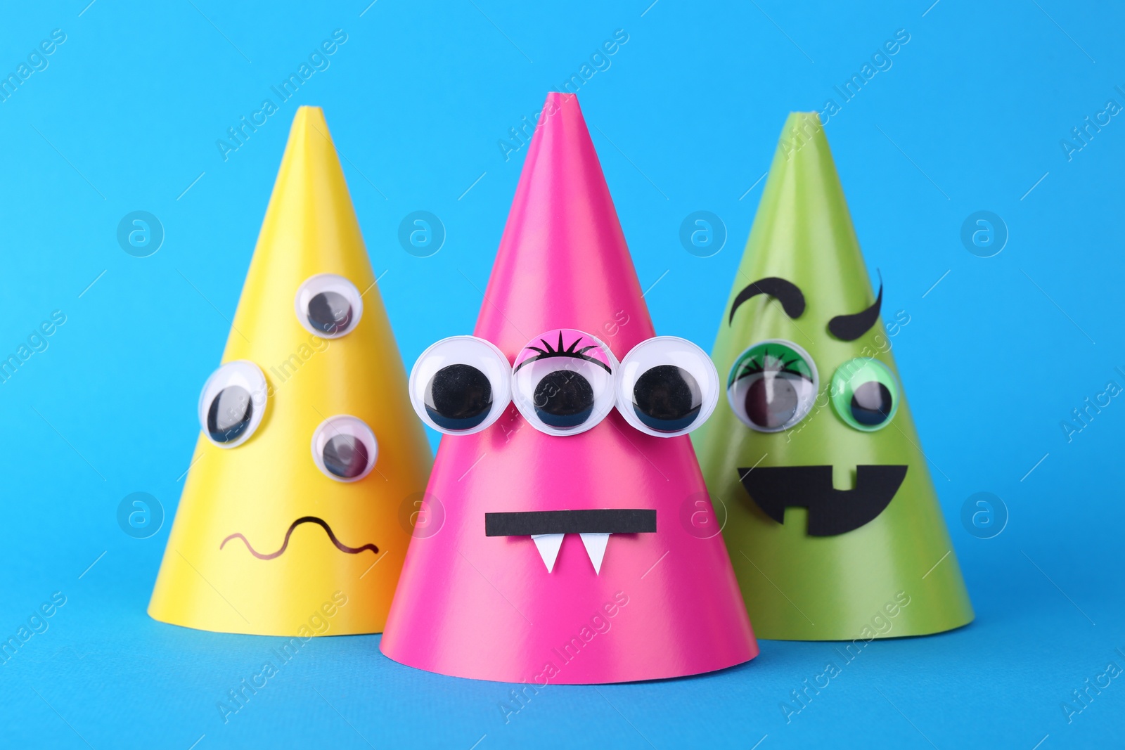 Photo of Spooky paper monsters on light blue background. Halloween decoration