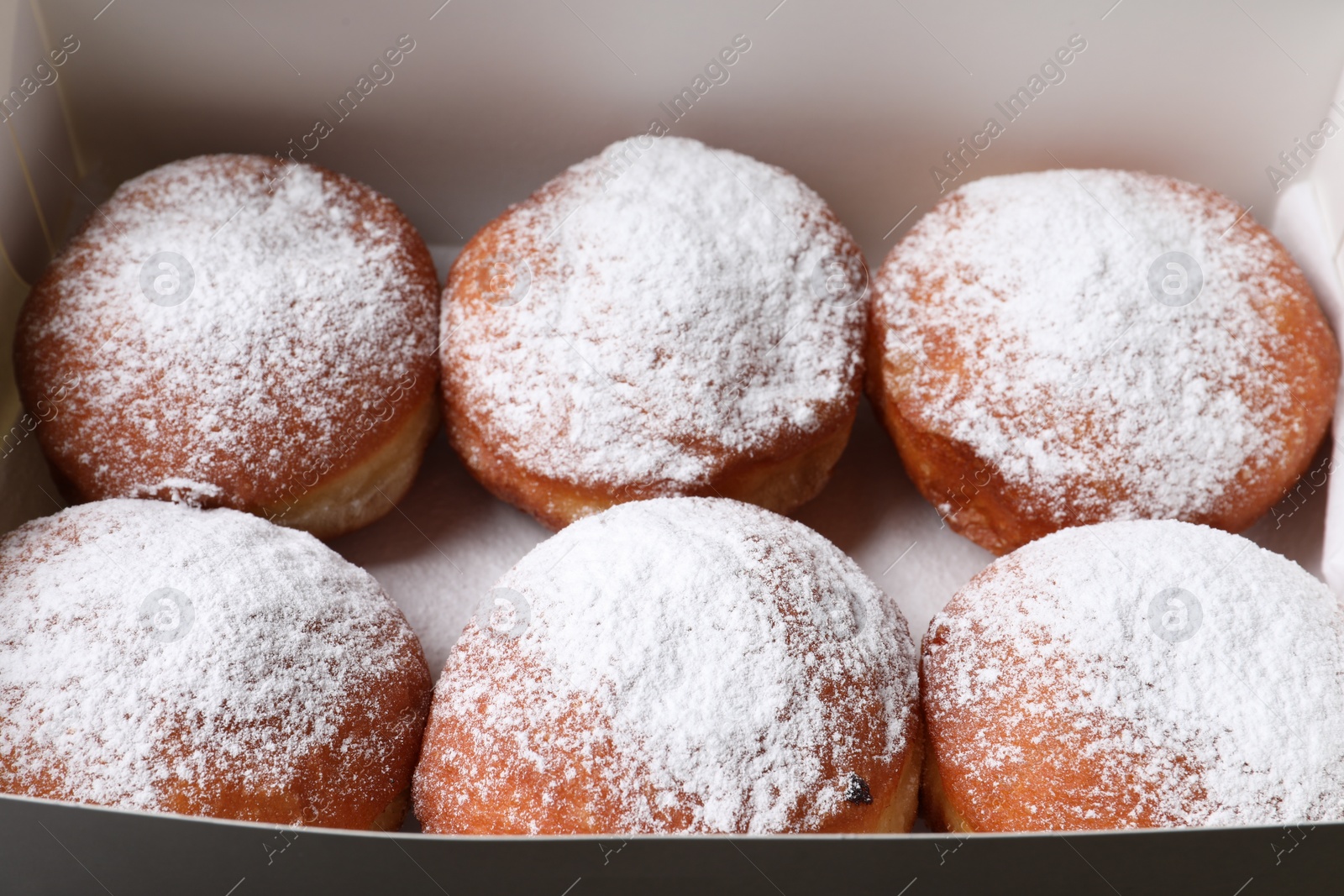 Photo of Delicious sweet buns with powdered sugar in box, closeup