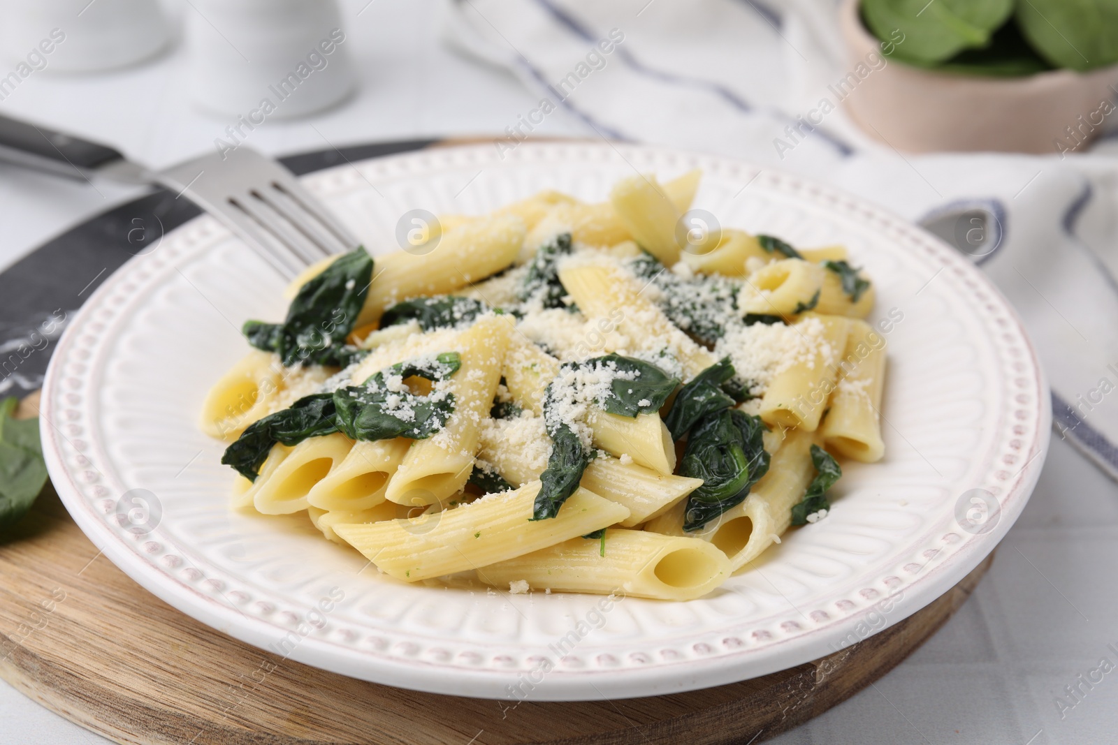 Photo of Tasty pasta with spinach and cheese on white tiled table, closeup