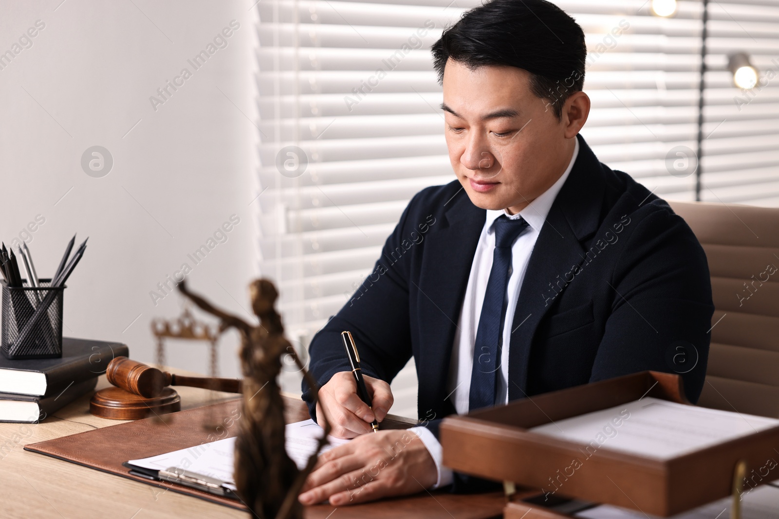 Photo of Notary writing notes at wooden table in office