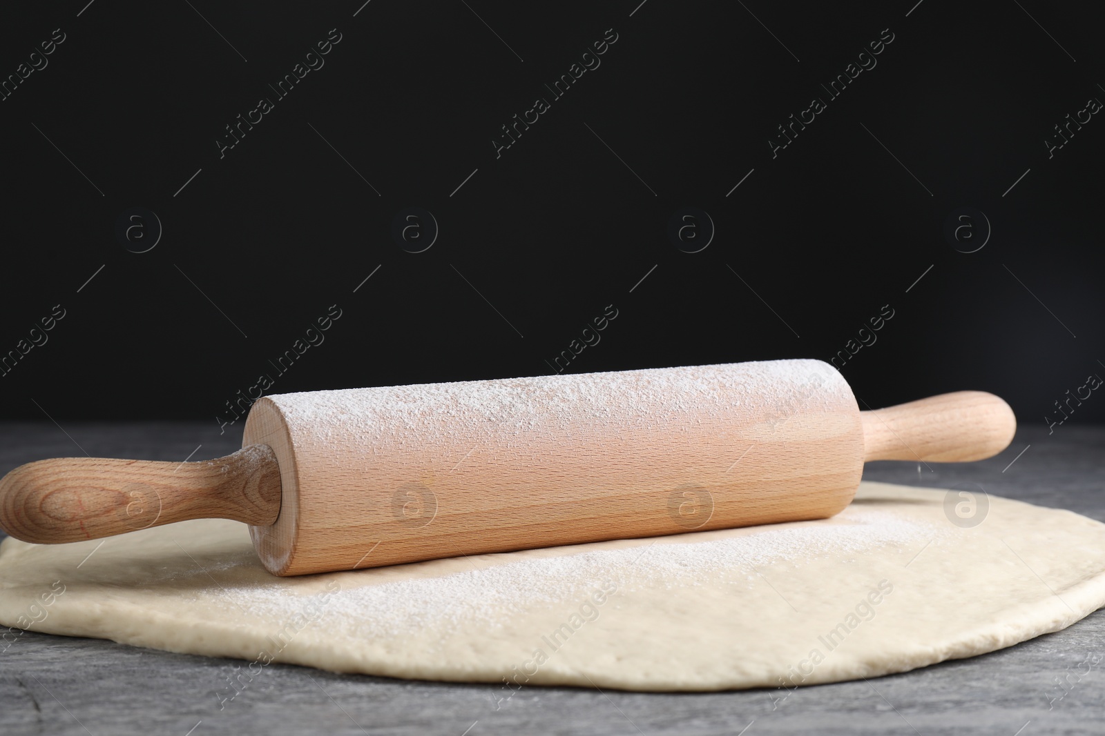 Photo of Raw dough and rolling pin on grey table