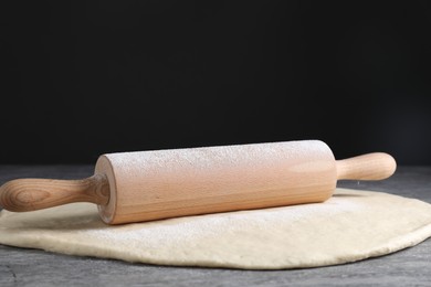 Photo of Raw dough and rolling pin on grey table