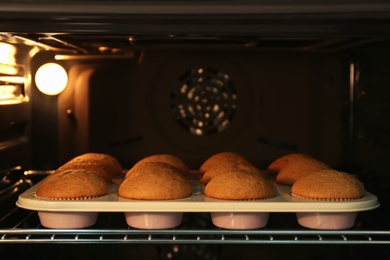 Photo of Baking pan with cupcakes in modern oven