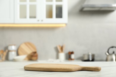Wooden cutting board on white table in kitchen. Space for text