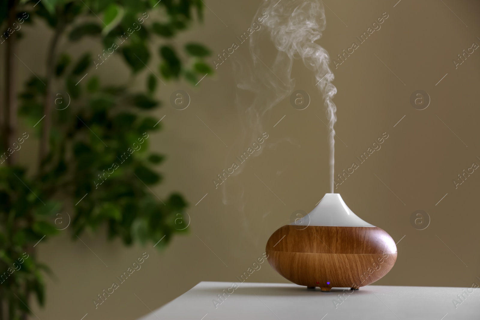 Photo of Aroma oil diffuser lamp on table against blurred background